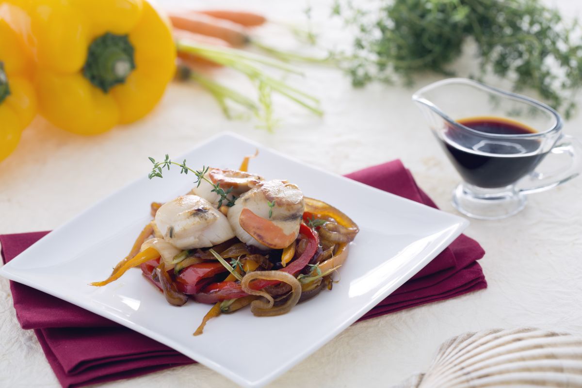 Jakobsmuscheln auf einem Bett aus karamellisierten Zwiebeln mit Karotten und Paprika in Sojasauce