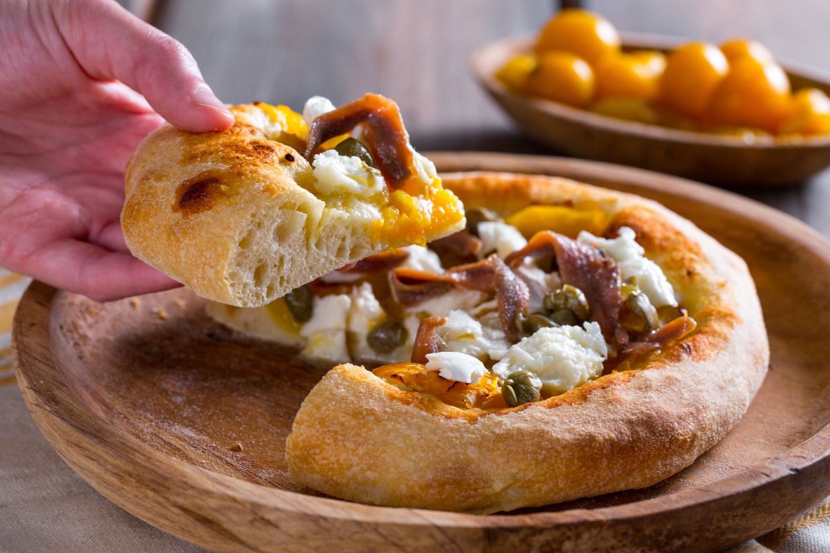 Pizza mit gelben Kirschtomaten, Sardellen und Kapern