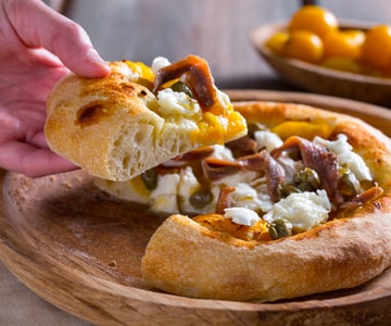 Pizza mit gelben Kirschtomaten, Sardellen und Kapern