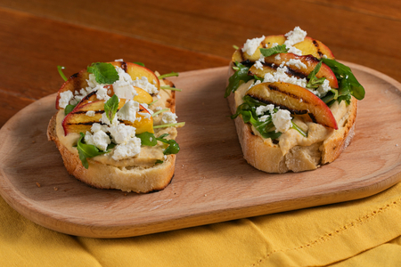 Crostone mit Hummus, gegrillten Pfirsichen, Feta und Rucola