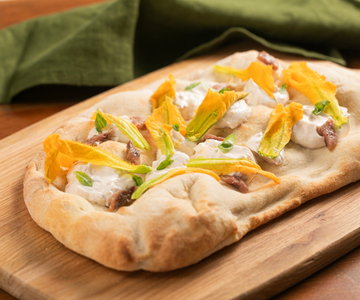 Pinsa mit Zucchiniblüten, Sardellen und Käsecreme