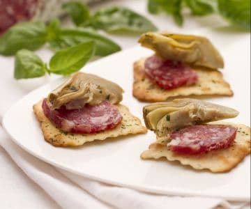 Artischocken und Salami auf Olivencrackern