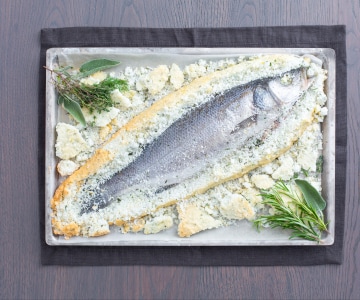 Wolfsbarsch (Seebarsch) mit Kräutern in Salzkruste