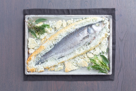 Wolfsbarsch (Seebarsch) mit Kräutern in Salzkruste